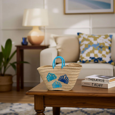 Handwoven Moroccan straw tote bag with blue shell embroidery and turquoise braided handles